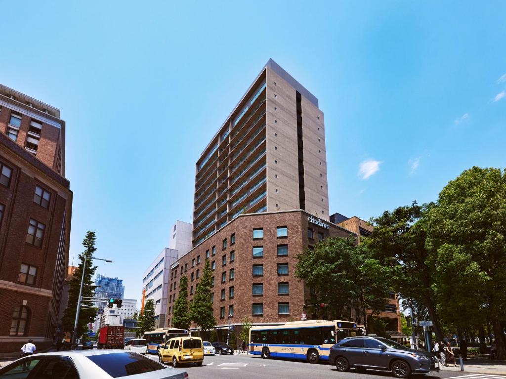 um edifício alto numa rua da cidade com carros em Citadines Harbour Front Yokohama em Yokohama