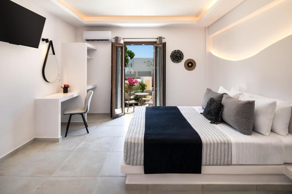 una camera con letto, scrivania e balcone di Santorinn Suites Fira a Firà