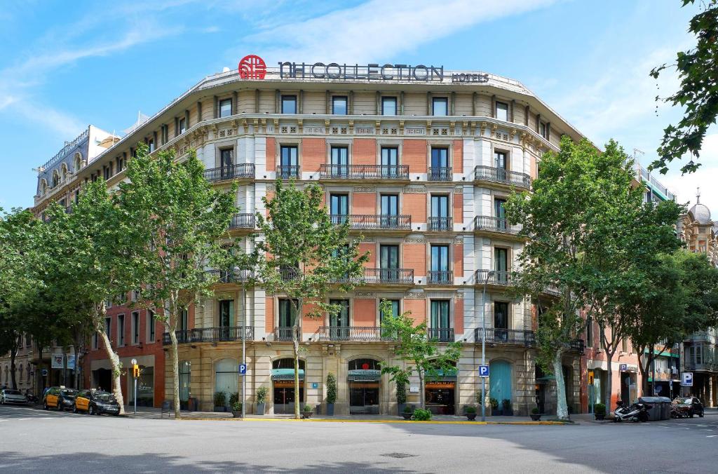 un grande edificio su una strada alberata di fronte di NH Collection Barcelona Podium a Barcellona