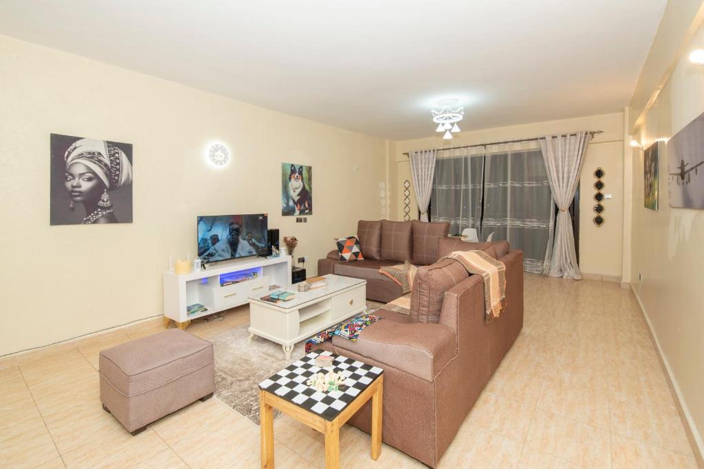 ein Wohnzimmer mit einem Sofa und einem TV in der Unterkunft Chrismario Homes in Nairobi