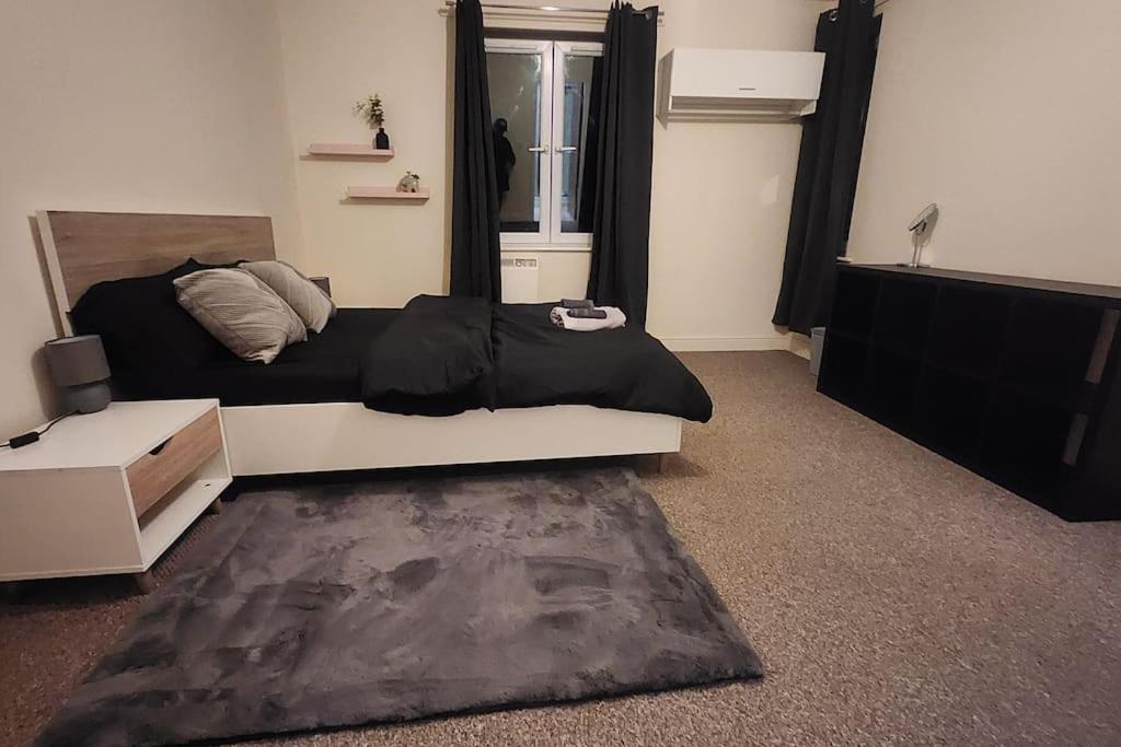 una camera da letto con un letto con lenzuola nere sopra di 2 bedroom apartment a Liverpool