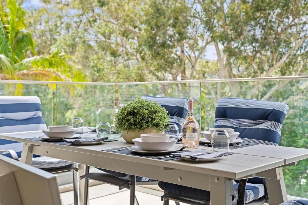 - une table avec des chaises et une bouteille de vin dans l'établissement Cool Coastal Pad with Panoramic Water Views, à Gosford