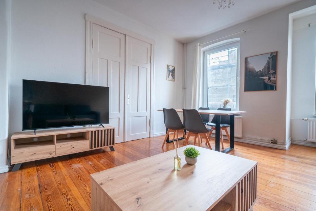 uma sala de estar com uma grande televisão e uma mesa em Großes Apartment mit 2 Balkonen zentral am Nordertor em Flensburg