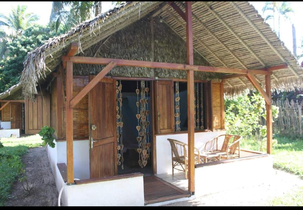 uma pequena casa com um telhado de palha e um alpendre em MAHAMBO BEACH hôtel em Mahambo