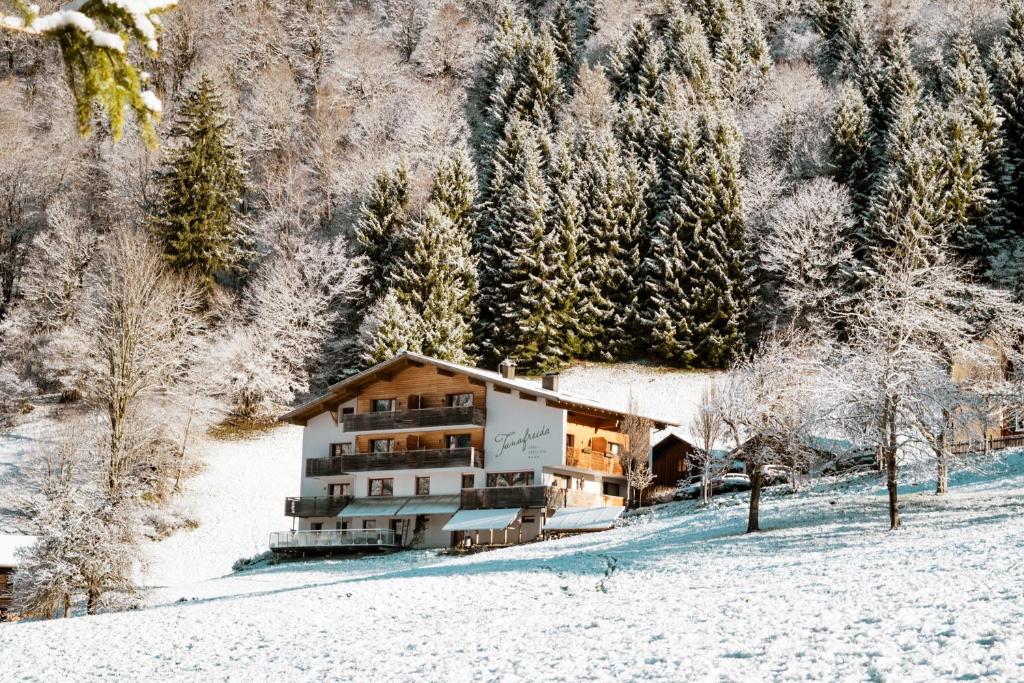 budynek w śniegu z drzewami w tle w obiekcie Tanafreida Apartments w mieście St. Gallenkirch