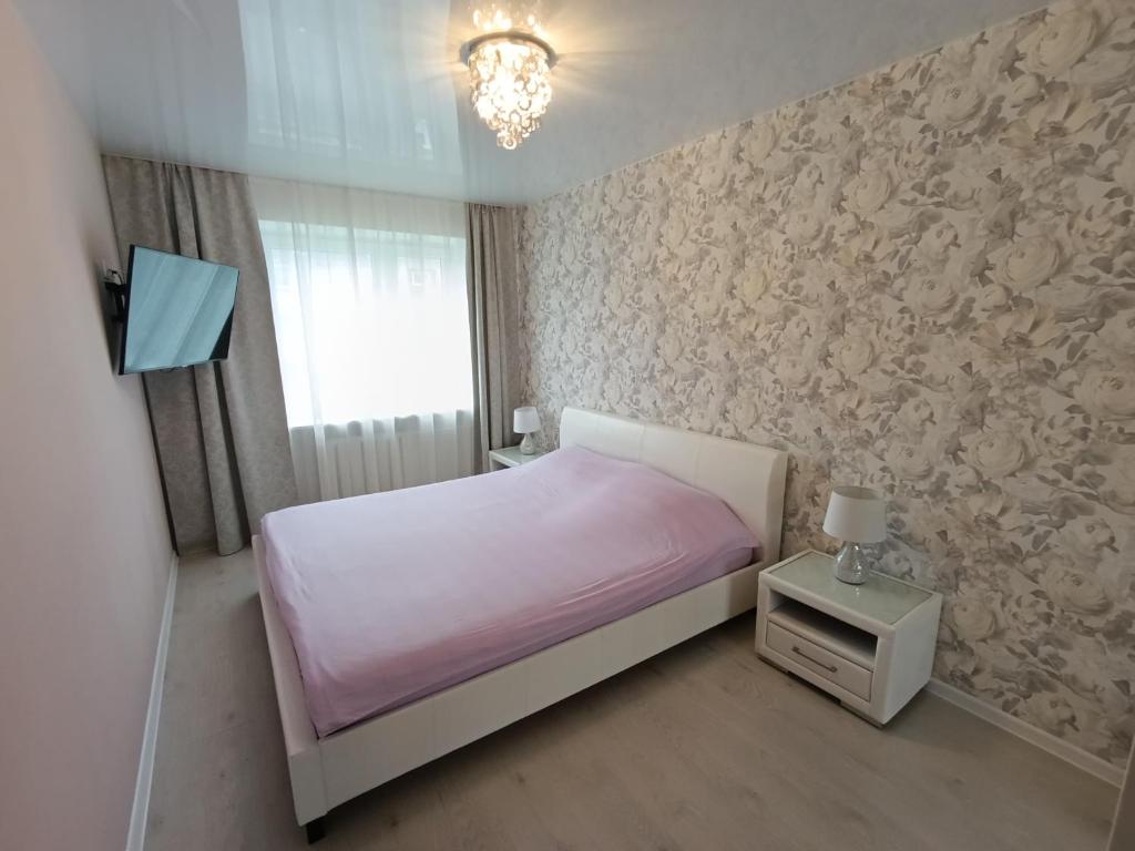 ein Schlafzimmer mit einem weißen Bett mit einer rosa Decke in der Unterkunft New Comfortable Apartment in center in Narva