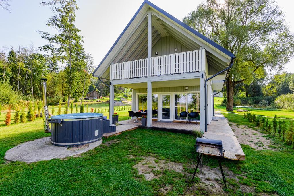 a small house with a porch and a yard at Namelis ant ežero kranto "Giliaus Elingas" in Tytuvėnai