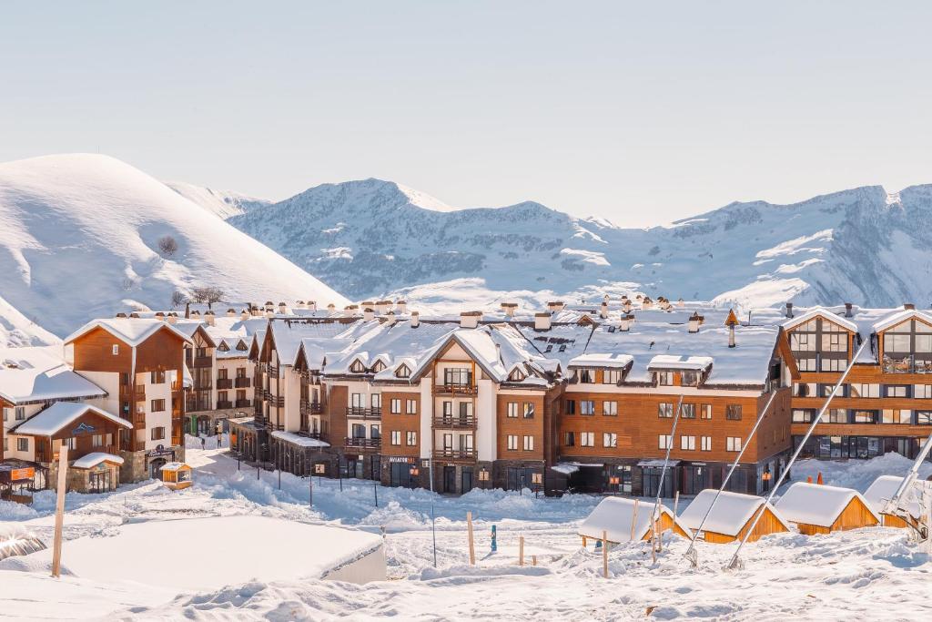 a resort in the snow with mountains in the background at PENTHOUSE BY GONDOLA 50 Meters, New Gudauri Suites in Gudauri