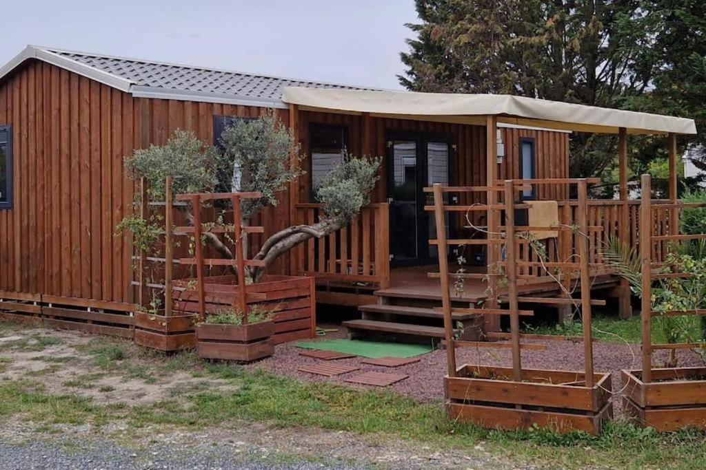 Cabaña de madera con cenador y algunos árboles en Mobilhome tout confort camping 4 étoiles, en La Teste-de-Buch