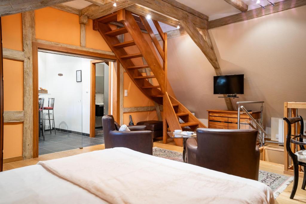 a bedroom with a staircase and a bed with chairs at Maison Rebleuthof Sauna & Fitness in Riquewihr