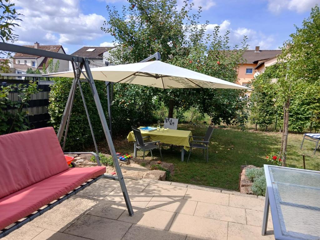 eine Terrasse mit einem Tisch und einem Sonnenschirm in der Unterkunft Ferienwohnung Gartenblick Altlußheim - Netflix - parken - Küche - Klimaanlage - Shuttle zum Hockenheimring in Altlußheim