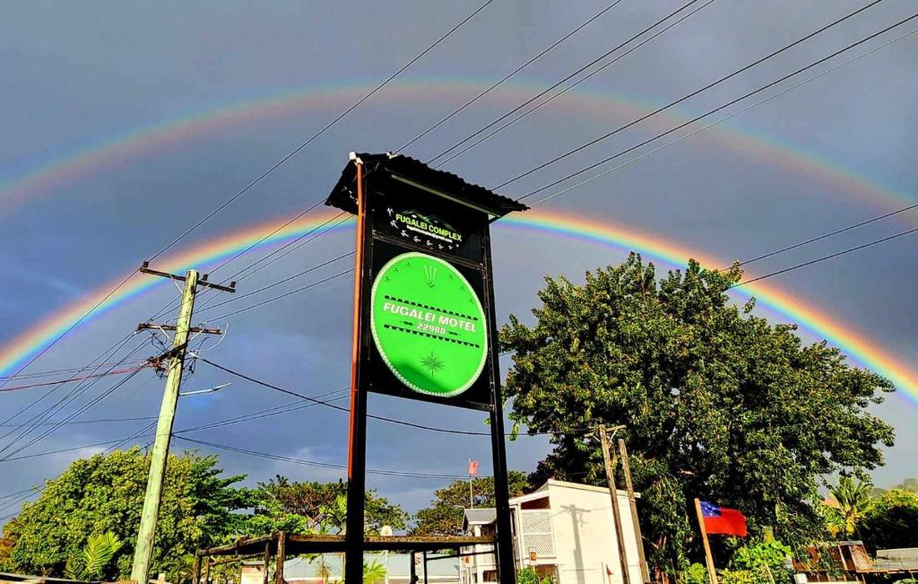 een regenboog in de lucht met een bord voor een straat bij Fugalei Motel in Apia