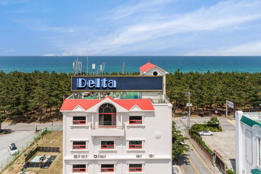 un edificio blanco con un cartel al lado del océano en Delta Hotel, en Gangneung