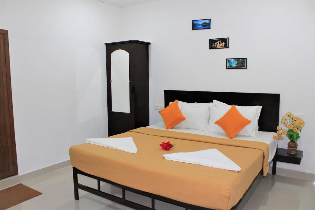 a bedroom with a large bed with orange and white pillows at SpiceGreen Homestay,Thekkady in Thekkady