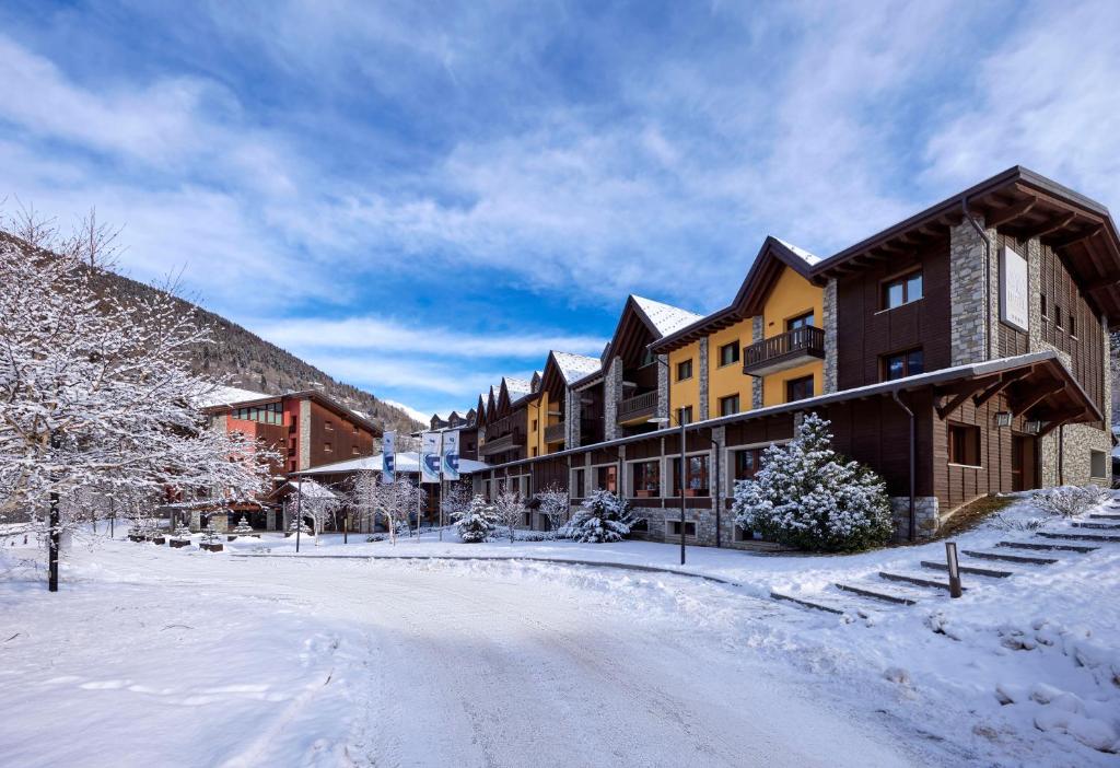 une rue enneigée dans une ville avec des bâtiments dans l'établissement Blu Hotel Acquaseria, à Ponte di Legno