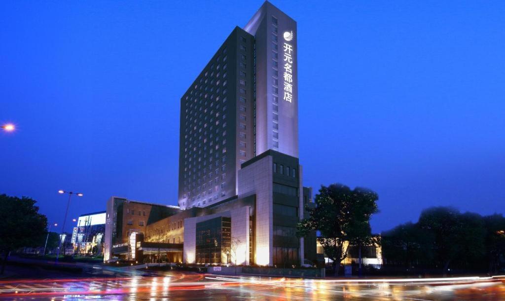 un edificio alto con luces encendidas por la noche en Grand New Century Hotel Binhai Tianjin, en Binhai