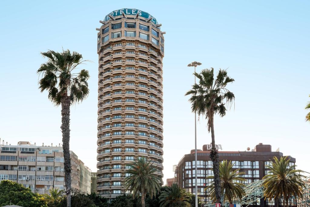 um edifício alto com palmeiras em frente em AC Hotel Gran Canaria by Marriott em Las Palmas de Gran Canárias