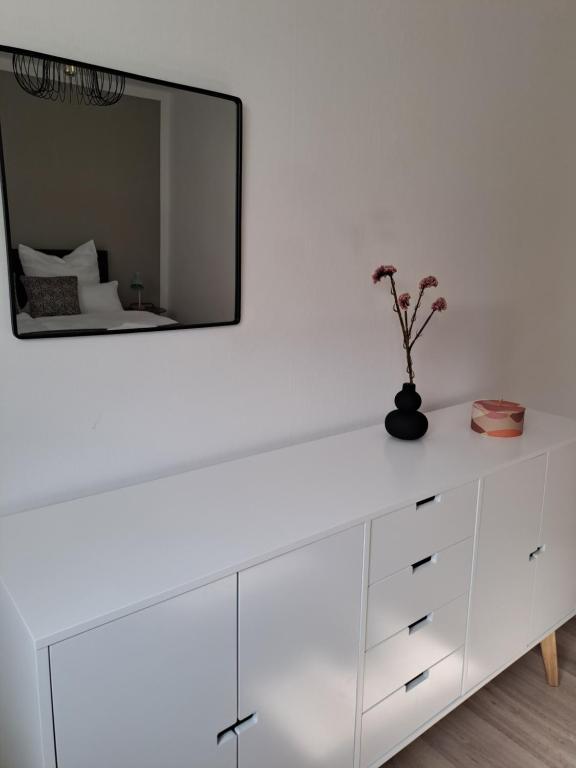 een witte dressoir met een spiegel aan de muur bij Apartment Seeblick in Bad Salzungen