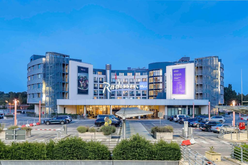 ein großes Gebäude mit Autos auf einem Parkplatz in der Unterkunft Radisson Blu Hotel, Hamburg Airport in Hamburg