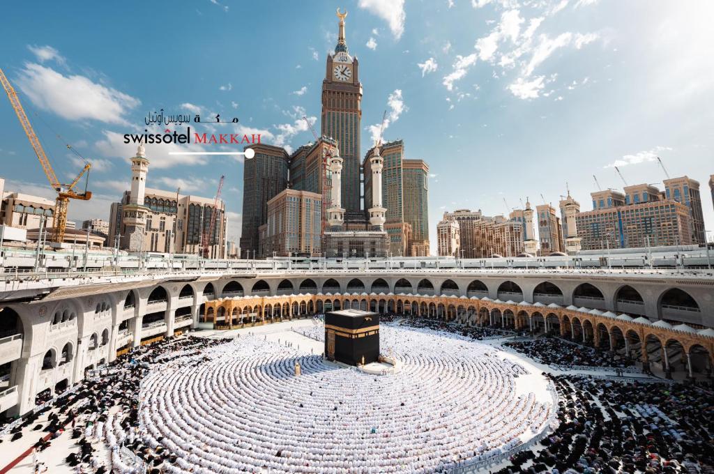 a large crowd of people in a stadium with a clock tower at Swissotel Makkah in Makkah