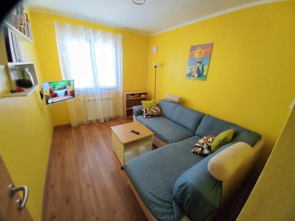 ein Wohnzimmer mit einem blauen Sofa und gelben Wänden in der Unterkunft Apartma Vita in Izola