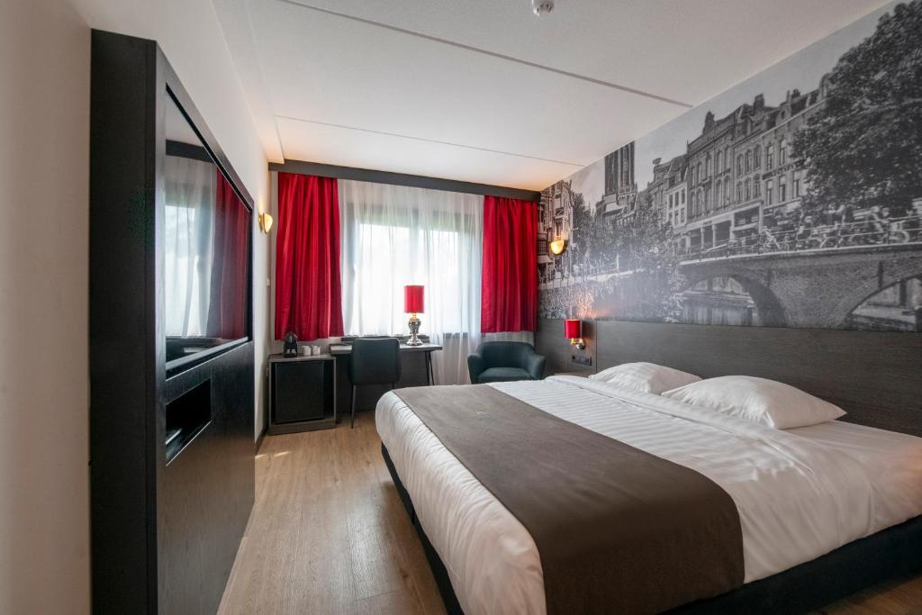 een hotelkamer met een groot bed en een televisie bij Bastion Hotel Barendrecht in Barendrecht