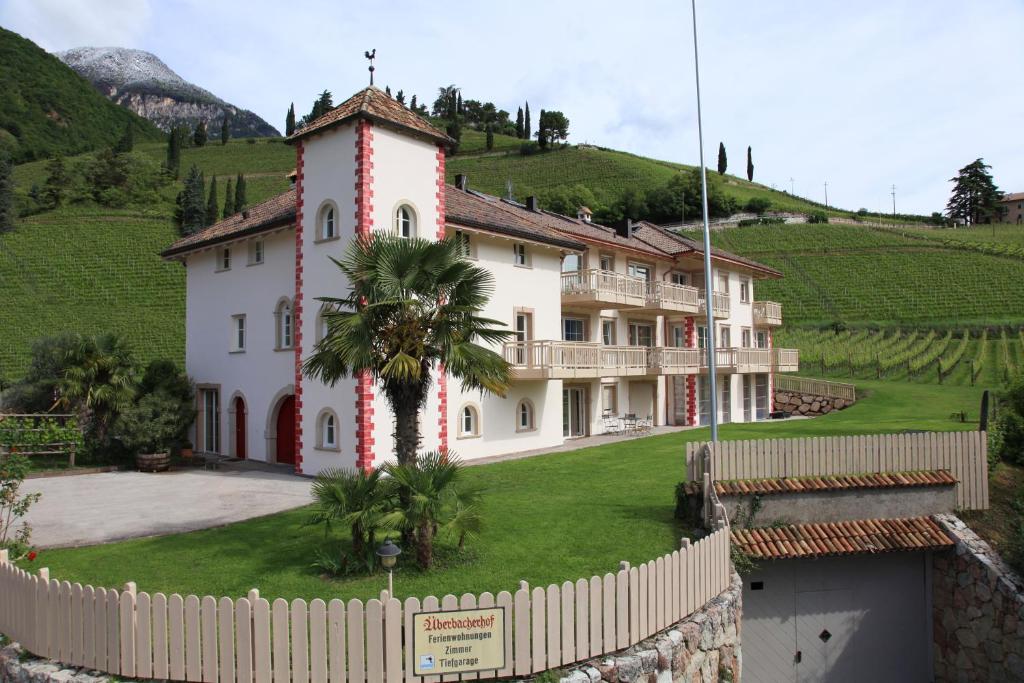 una grande casa bianca con una palma di fronte di Überbacherhof a Termeno