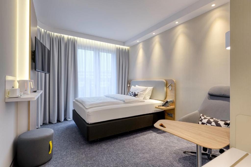 ein Hotelzimmer mit einem Bett und einem Stuhl in der Unterkunft Holiday Inn Express Munich Airport - Erding, an IHG Hotel in Erding