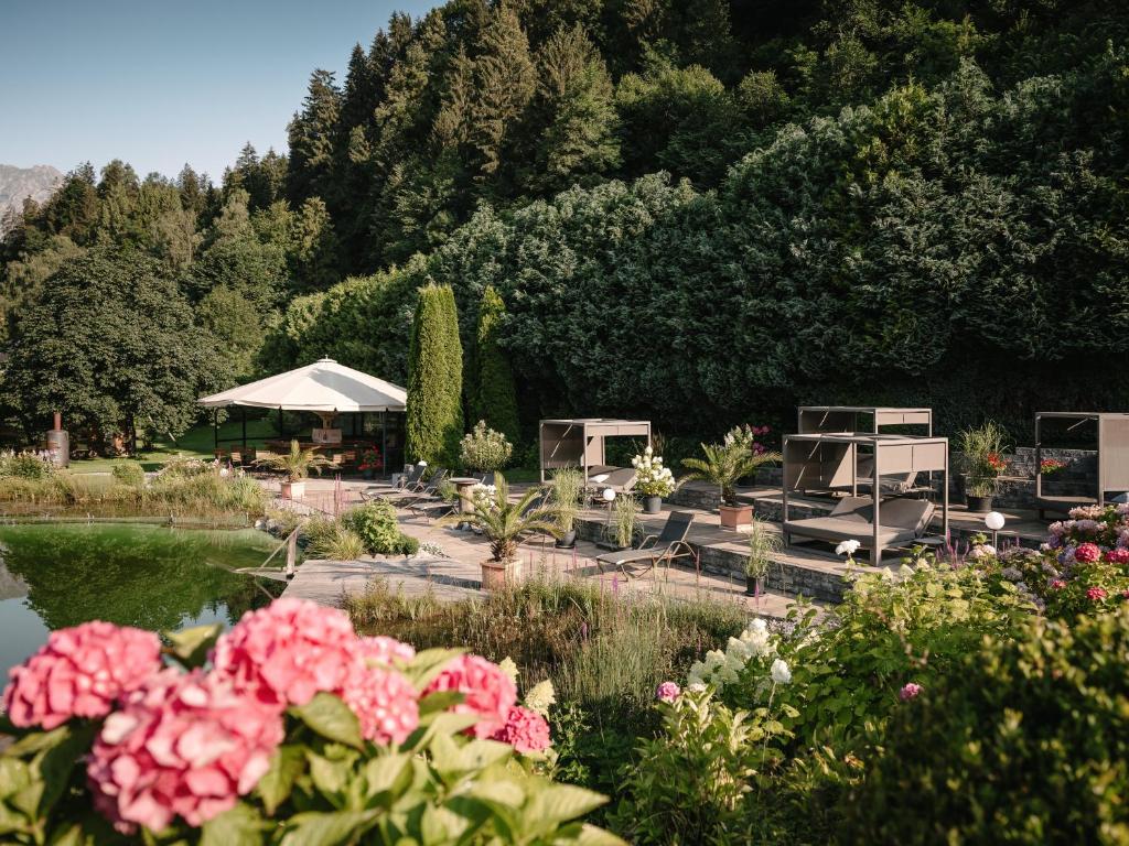 een tuin met bloemen en een vijver en bomen bij Hotel Vitalquelle Montafon in Schruns