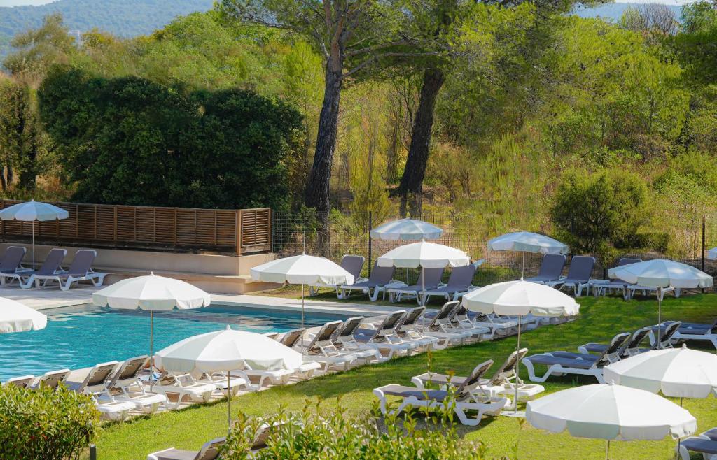 a swimming pool with chairs and umbrellas and a pool at Grand Prix Hôtel & Restaurant in Le Castellet