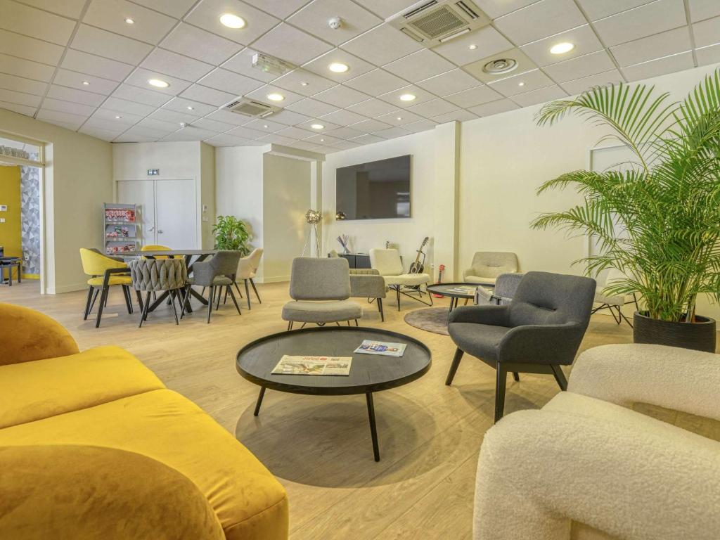 una sala de espera con sofás, sillas y una mesa en ibis Cholet, en Cholet