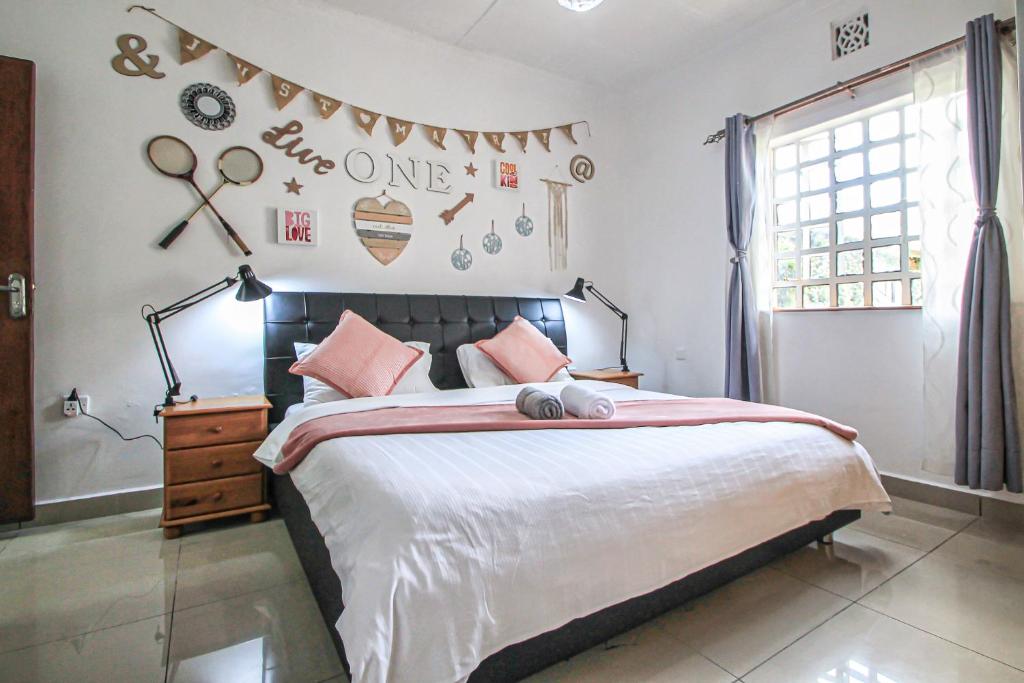 una camera da letto con un grande letto con cuscini rosa di North Manor Nakuru a Nakuru