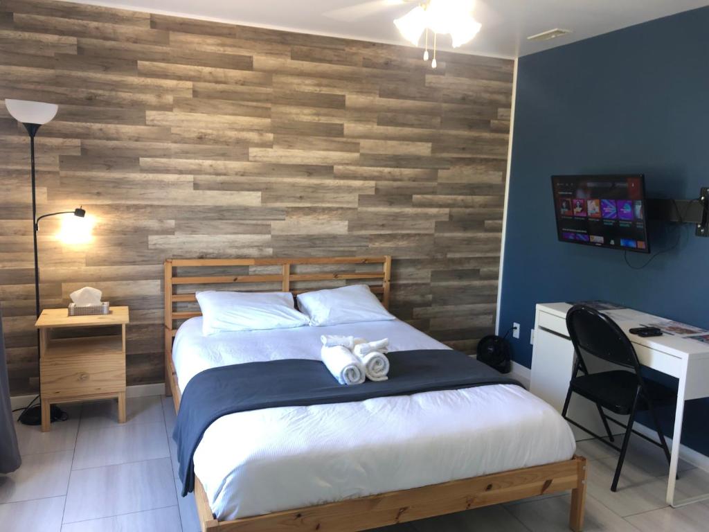 een slaapkamer met een bed en een houten muur bij Bleu Mer, hôtel & résidences in Carleton sur Mer