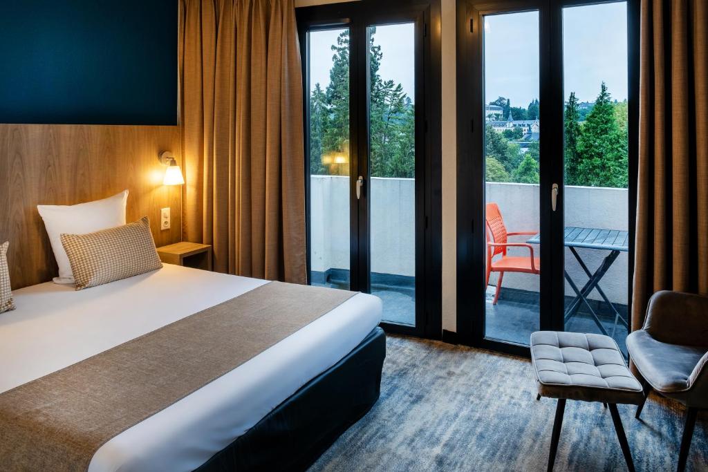 una camera con letto e balcone di Hôtel Panorama a Lourdes