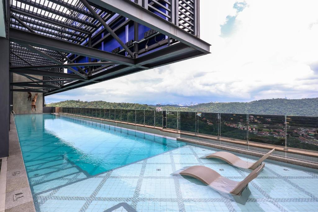 una piscina con due sedie a sdraio in cima a un edificio di Mossaz Suites by Mykey Global a Petaling Jaya