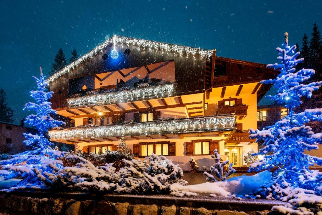 un edificio decorado con luces de Navidad en la nieve en Hotel Lajadira & Spa, en Cortina dʼAmpezzo