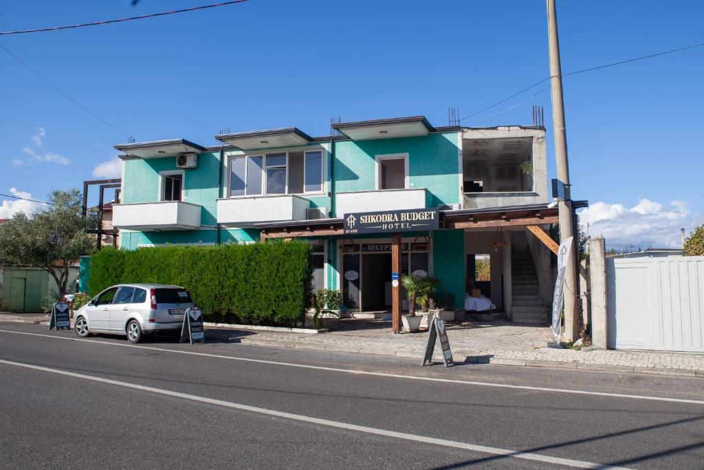 a white car parked in front of a building at Shkodra Budget Hotel in Shkodër