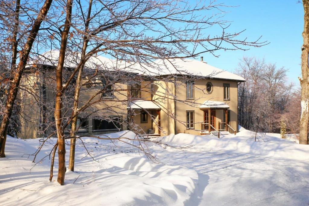 une maison avec de la neige devant elle dans l'établissement Blue Hill Pool spa game room mountain view, à Morin Heights