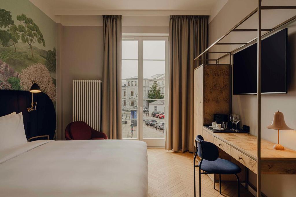 a hotel room with a bed and a desk and a window at Flaner Hotel, WorldHotels Crafted in Warsaw