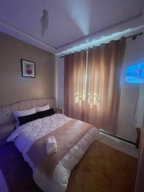 um quarto com uma cama branca e uma janela em hotel darna with air conditioning em Er Rachidia