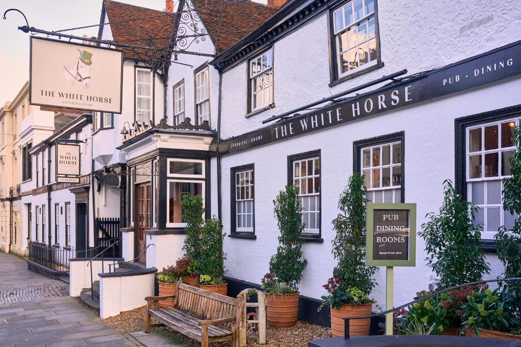 ein weißes Haus mit einer Bank davor in der Unterkunft The White Horse in Dorking