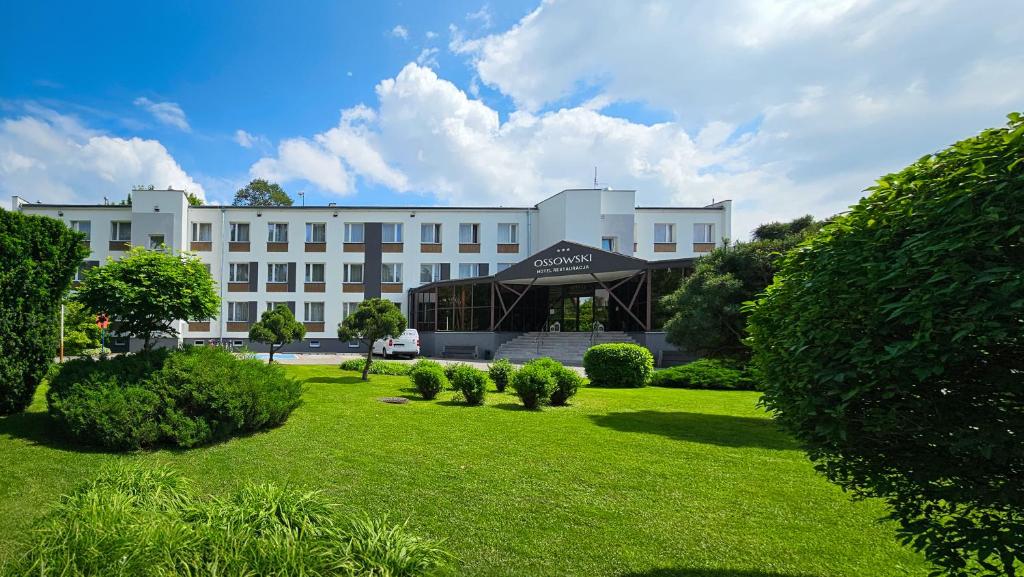 un grande edificio bianco con un prato di fronte di Hotel Ossowski a Swarzędz