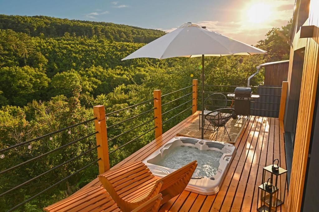 uma banheira de hidromassagem num deque com um guarda-sol em Mátra Forest Resort em Matrafured