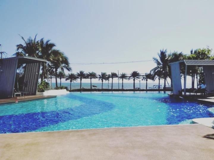 a large swimming pool with palm trees in the background at studio room seaview jomtien in Jomtien Beach