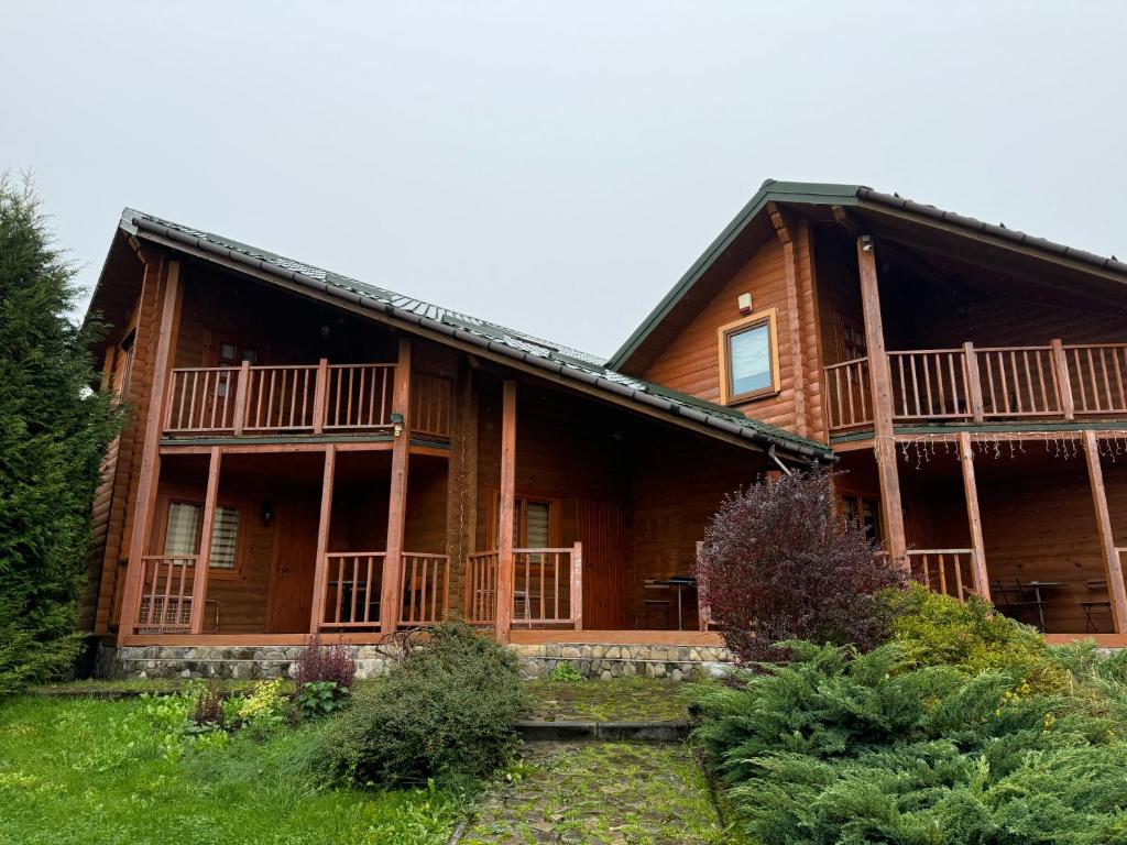 a large wooden house with a large porch at Arnika in Skhidnitsa