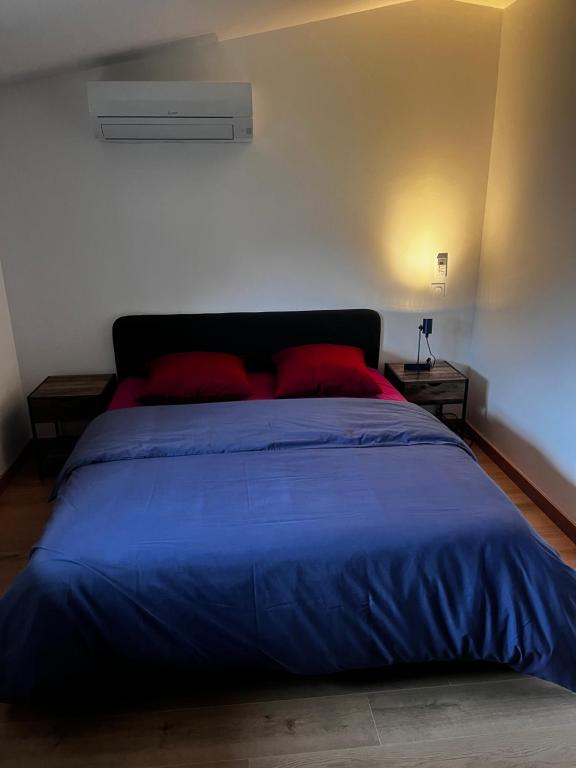 een slaapkamer met een blauw bed met 2 rode kussens bij edendebruges in Bruges