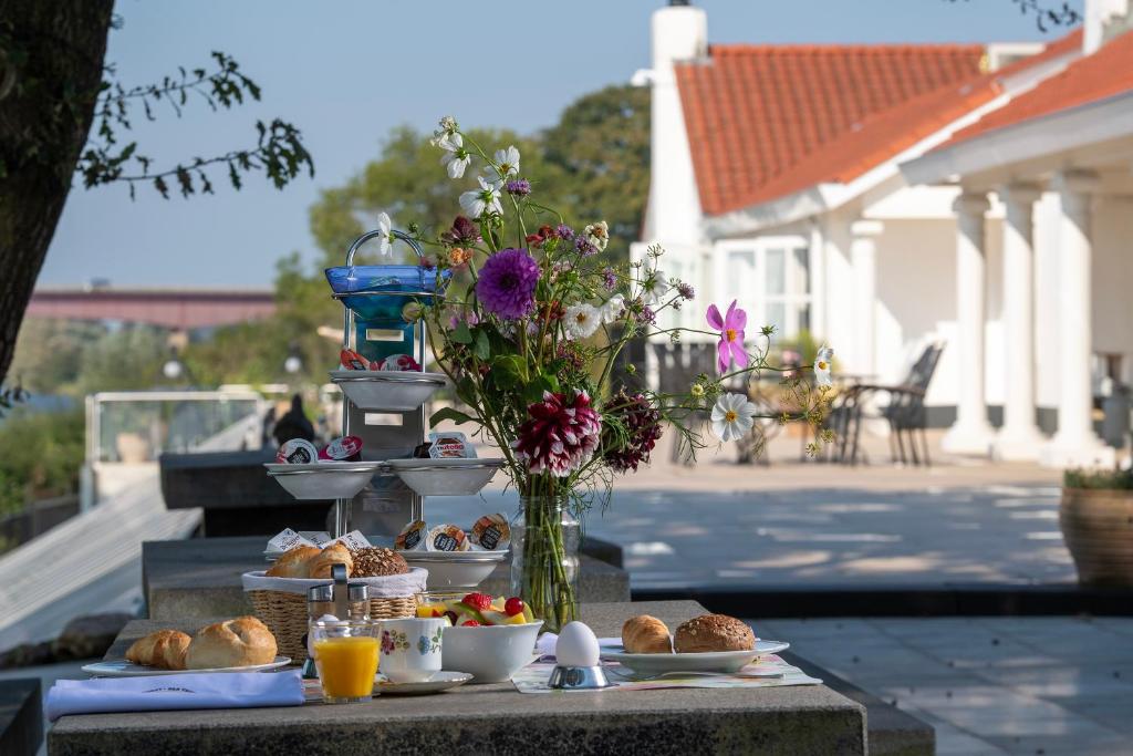 uma mesa com comida e um vaso de flores em Bed & Breakfast Trouwborst em Rhenen