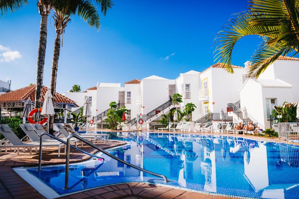 una piscina con palmeras y edificios en Apartamentos Parque del Sol, en Adeje