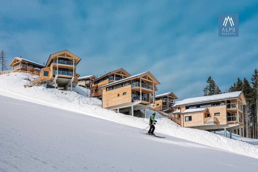 a person is skiing in front of a ski lodge at Alpenchalets Reiteralm by ALPS RESORTS in Schladming