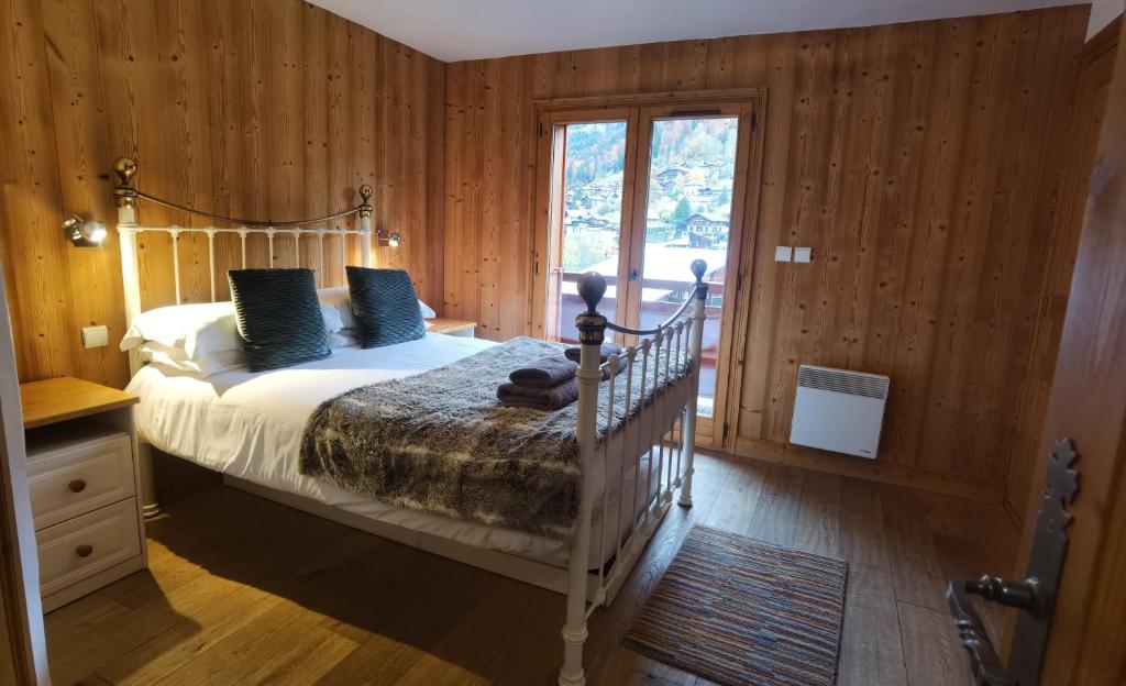 een slaapkamer met een bed met blauwe kussens en een raam bij Slemish Apartment in Morzine